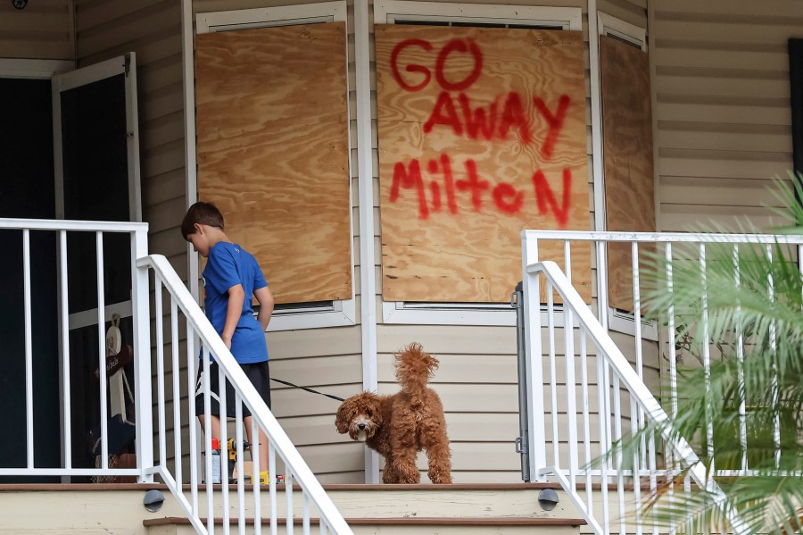 Noah Weibel and his dog Cookie climb the steps to their home as their family prepares for Hurricane Milton on Monday, Oct. 7, 2024, in Port Richey, Fla. 