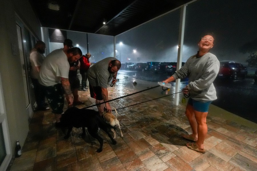 Amy Sapanara, right, of Pinellas, Fla., reacts as a group of tow truck drivers from Northeast Georgia greet her dogs, Frankie and Dudley, outside the hotel where they are all taking shelter during Hurricane Milton, Wednesday, Oct. 9, 2024, in Tampa, Fla.