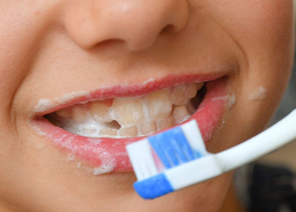 Image shows a child brushing his teeth.