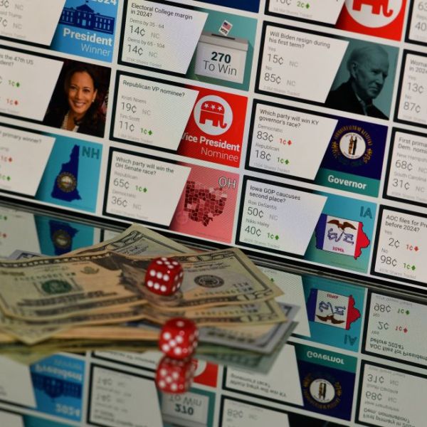 Illustration photo shows money and gambling dice in front of a screen showing political market odds