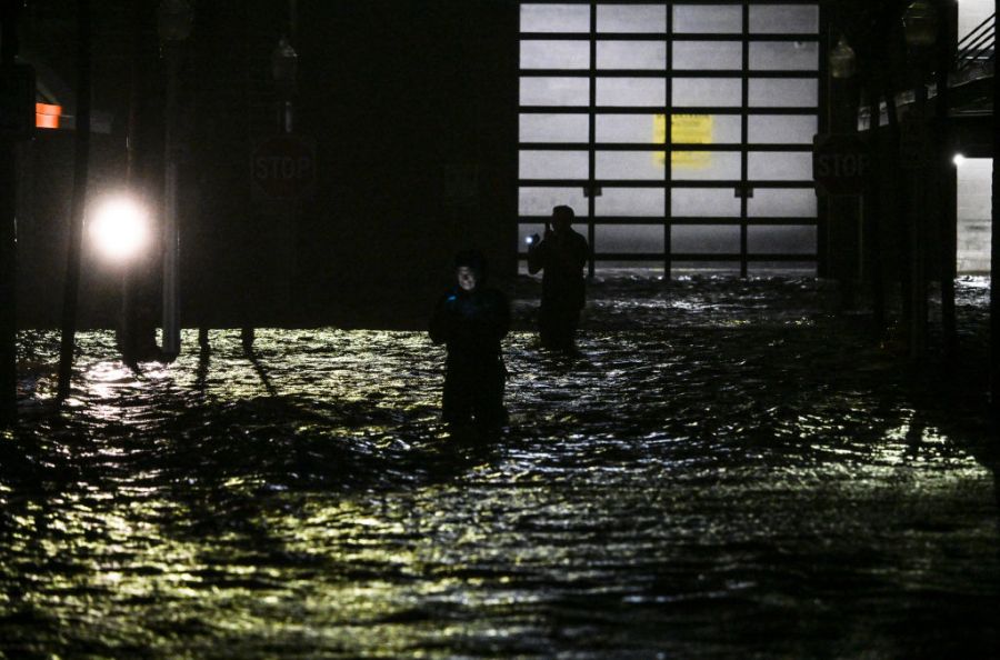 People take photos and videos as they walk through streets inundated by floodwaters after Hurricane Milton made landfall in Fort Myers, Florida, on October 9, 2024.