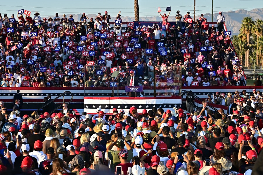 Former US President and Republican presidential candidate Donald Trump speaks during a campaign rally, surrounded by a crowd of people.