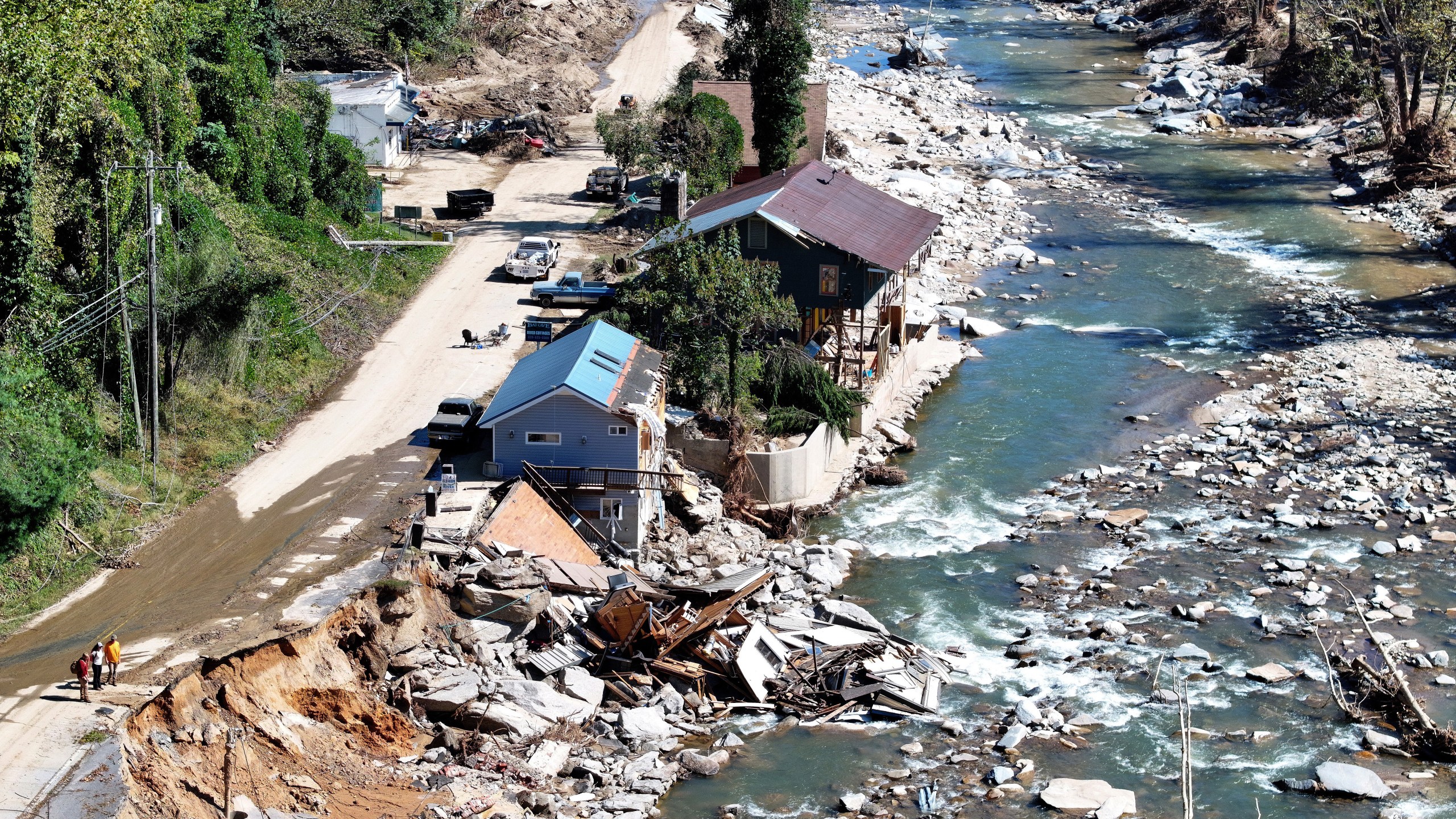 An aerial view of people standing near destroyed and damaged buildings in the aftermath of Hurricane Helene flooding on October 8, 2024 in Bat Cave, North Carolina.