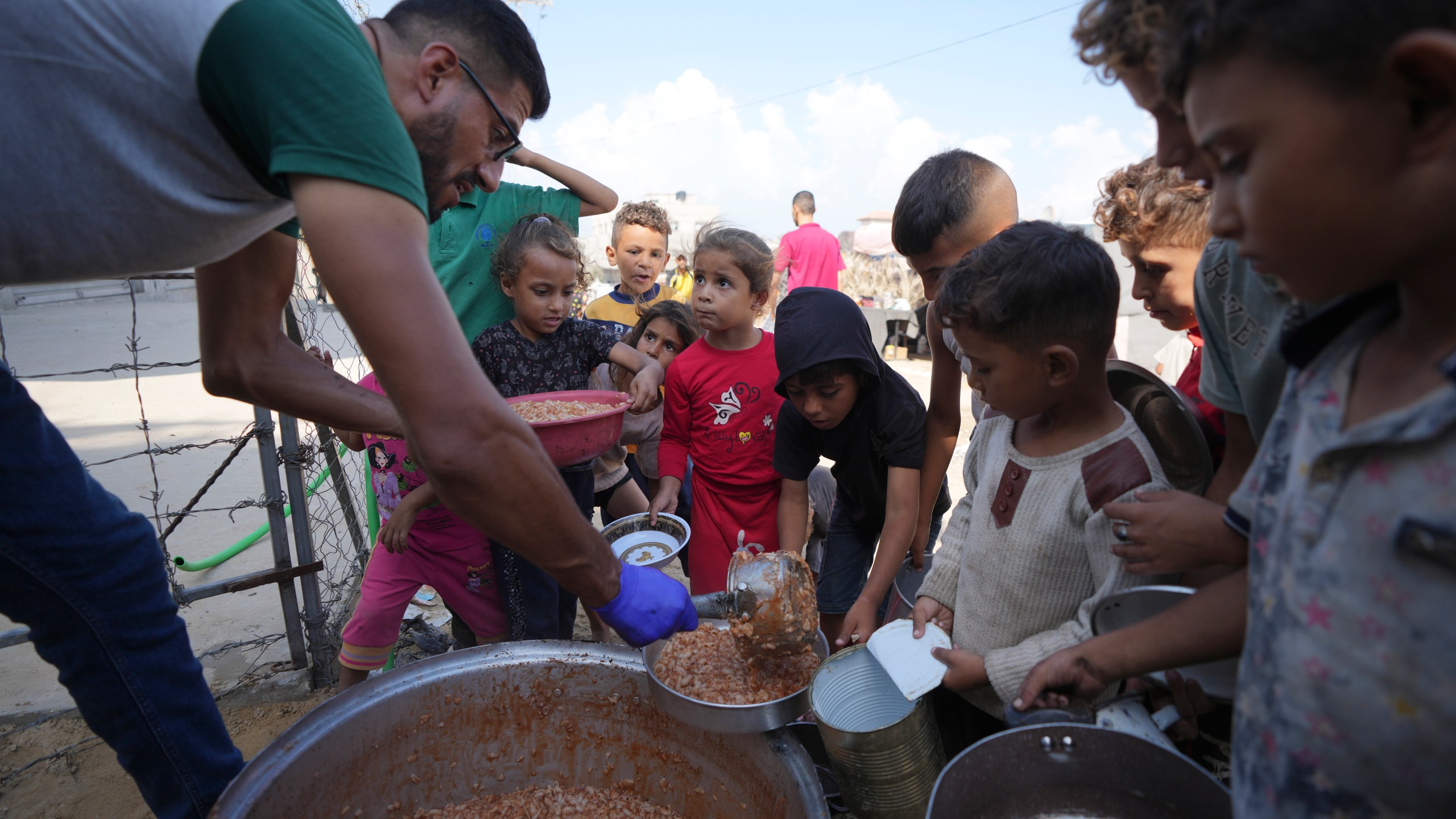 Displaced Palestinian children queue for food in a camp in Deir al-Balah, Gaza Strip, Friday, Oct. 18, 2024. (AP Photo/Abdel Kareem Hana)