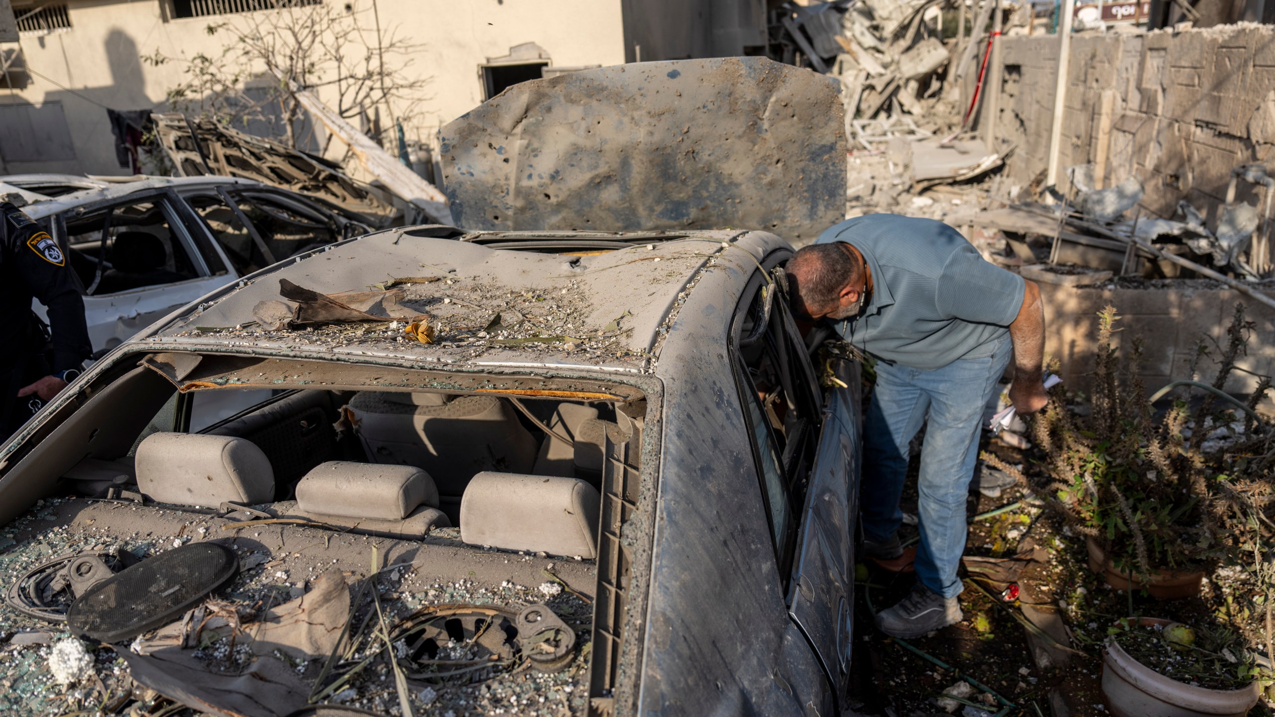 A man surveys damage to his car after projectiles fired from Lebanon hit a home in Tira, central Israel, Saturday, Nov. 2, 2024. (AP Photo/Ariel Schalit)