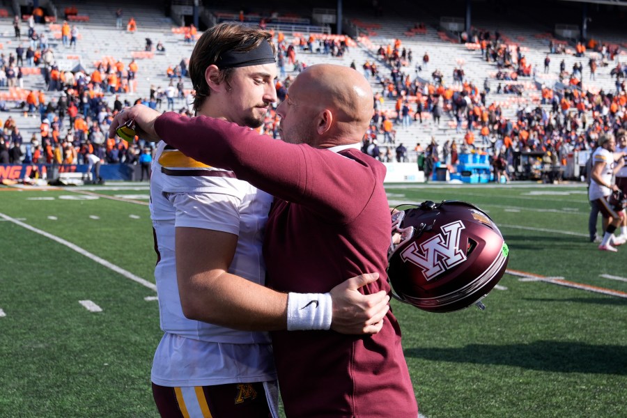 Minnesota head coach P.J. Fleck hugs quarterback Max Brosmer after the teams 25-17 win over Illinois in an NCAA college football game Saturday, Nov. 2, 2024, in Champaign, Ill. (AP Photo/Charles Rex Arbogast)