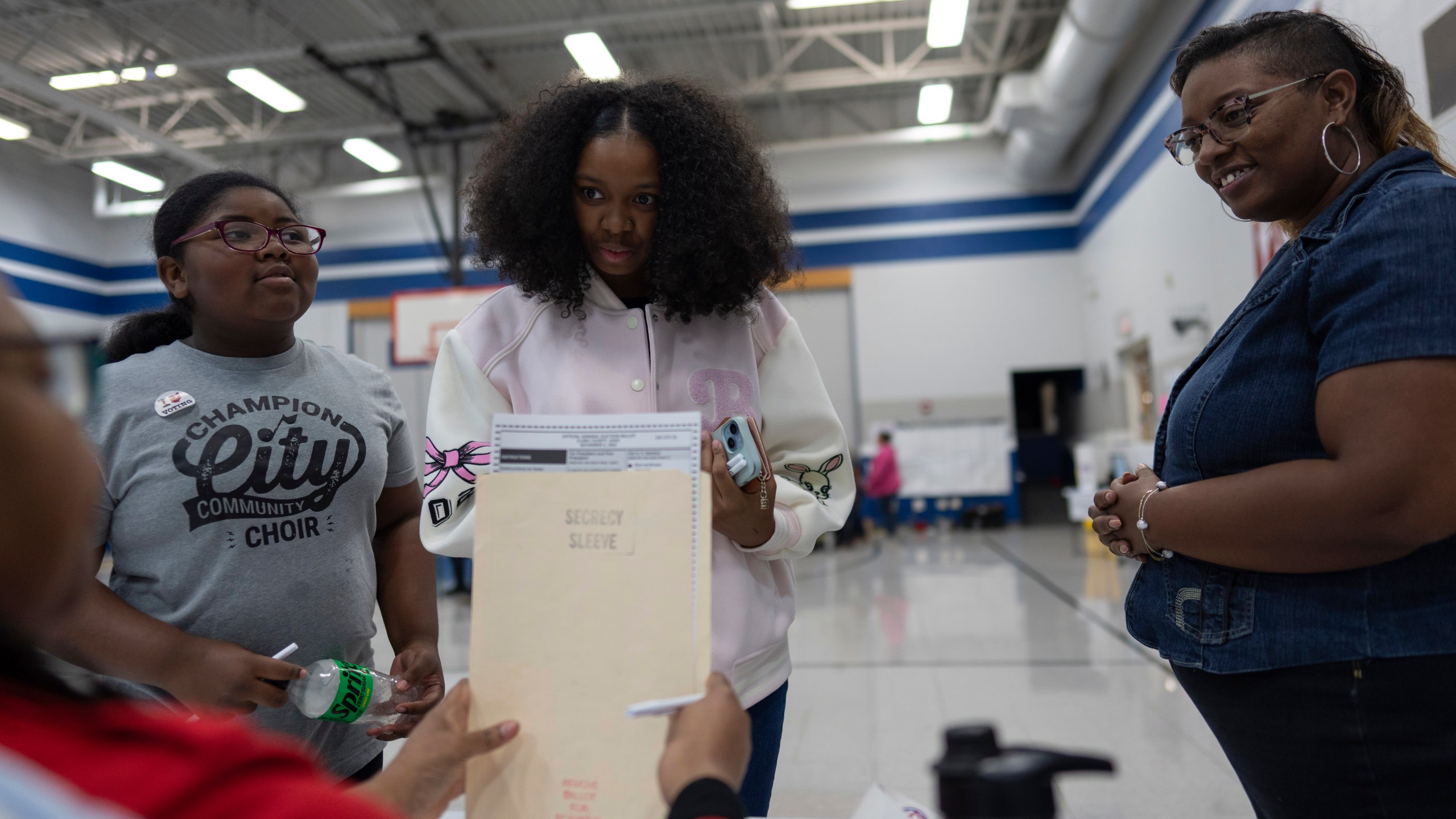 First-time voter Samaira Peterson, center, stands with her mother Khayesha Peterson, right, and her little sister Samaiya Peterson, left, as she prepares to vote at Warder Park-Wayne Elementary School on Election Day, Tuesday, Nov. 5, 2024, in Springfield, Ohio. (AP Photo/Carolyn Kaster)