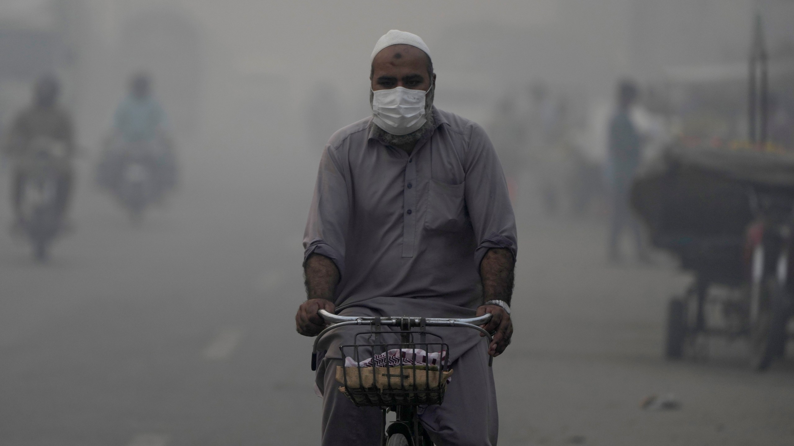 A cyclist, wearing mask, heads to his workplace as smog envelops the areas of Lahore, Pakistan, Wednesday, Nov. 6, 2024. (AP Photo/K.M. Chaudary)