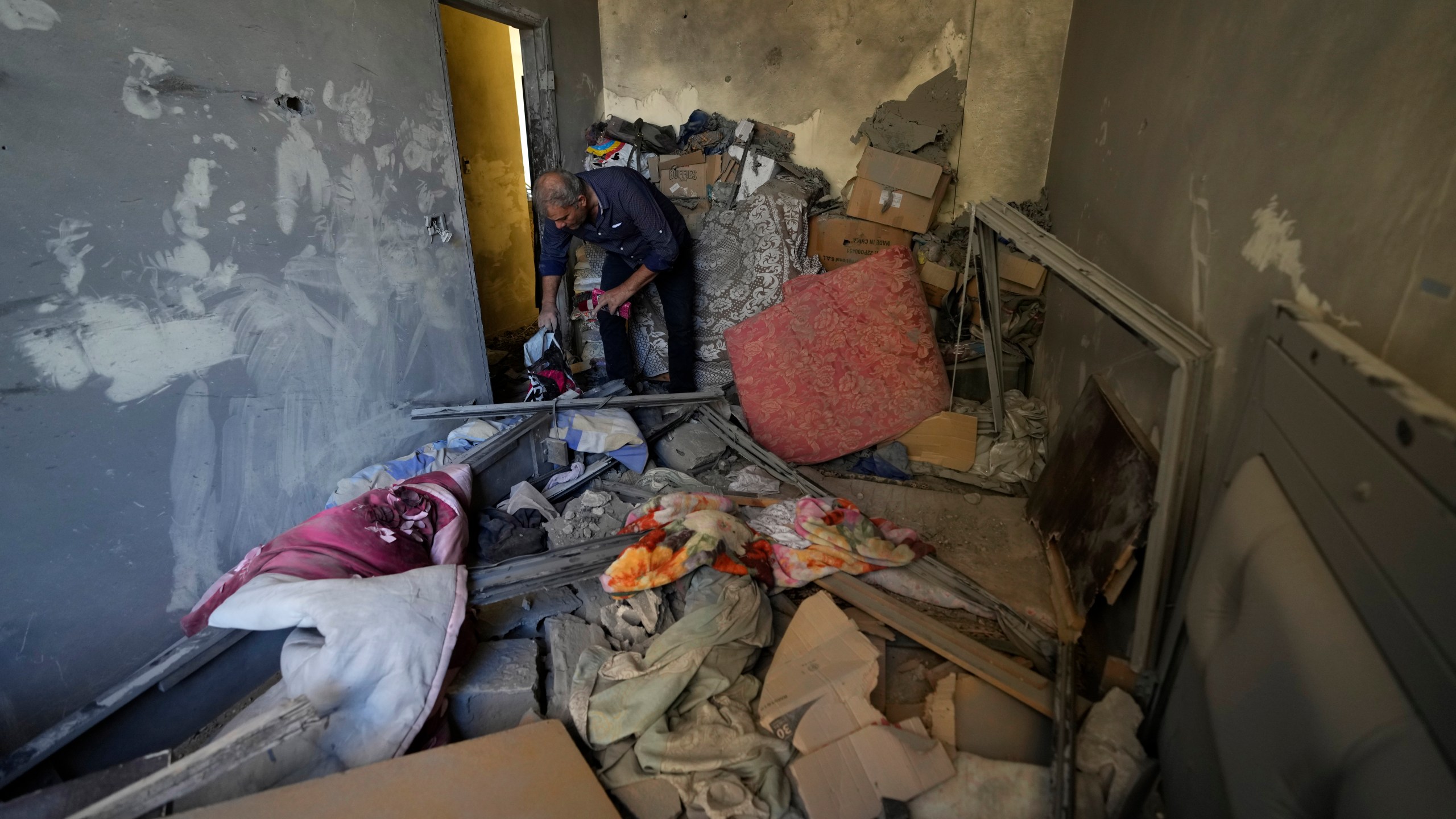 A resident of a building damaged in an Israeli airstrike on Tuesday night, returns to collect his family's belongings in Barja, Lebanon, Wednesday, Nov. 6, 2024. (AP Photo/Hassan Ammar)