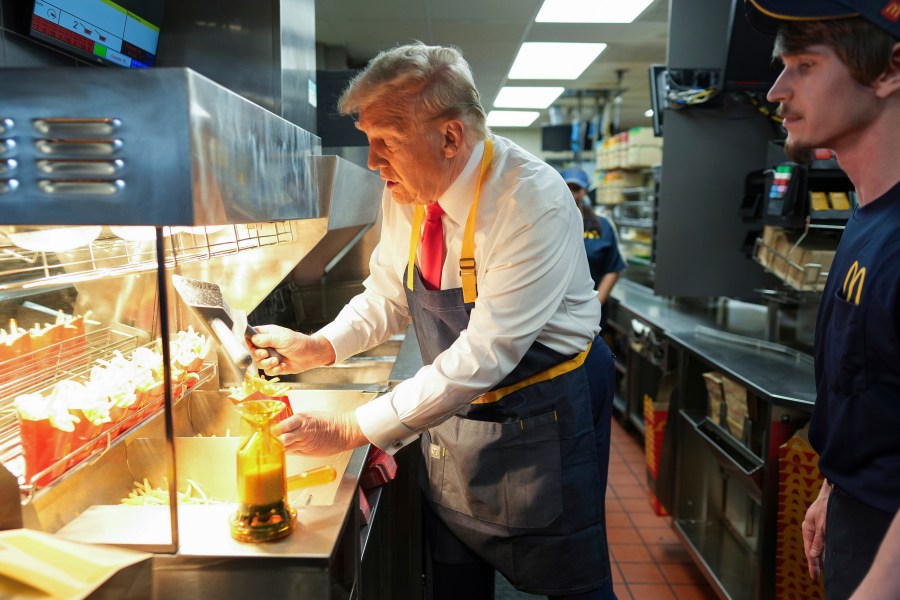 Republican presidential nominee former President Donald Trump serves french fries as an employee looks on during a visit to McDonald's in Feasterville-Trevose, Pa., Sunday, Oct. 20, 2024. (Doug Mills/The New York Times via AP, Pool)