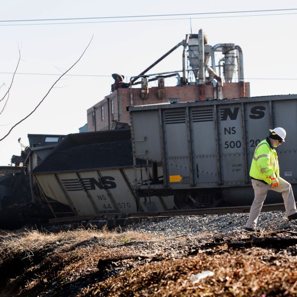 FILE - A Norfolk Southern worker walks next to the scene of a multi-car coal train derailment near Suffolk, Va., on Feb. 4, 2017. (Bill Tiernan/The Virginian-Pilot via AP, File)