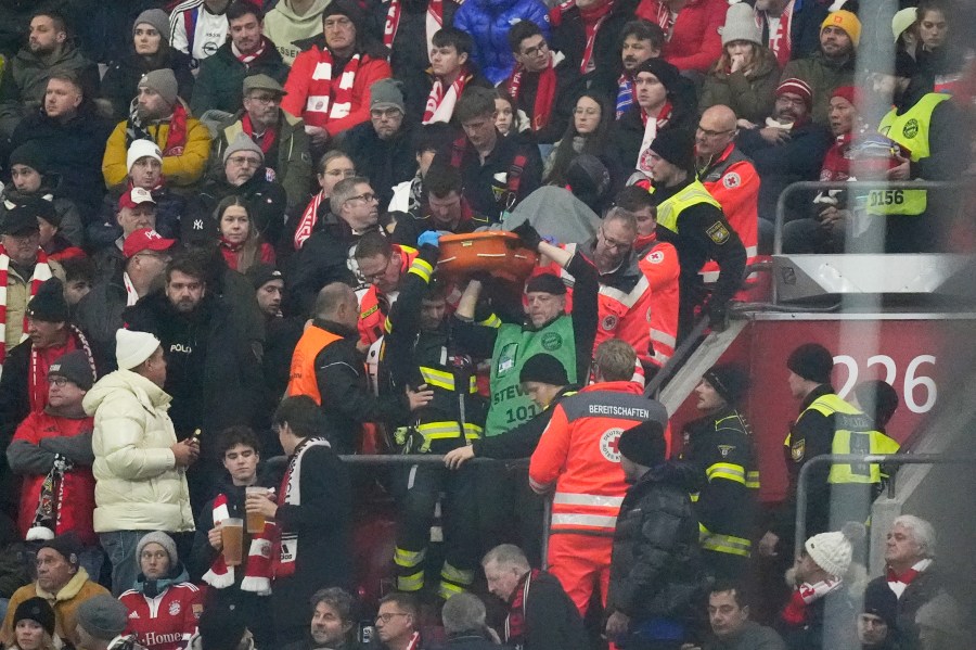 Police officers and paramedics carry a stretcher down the stands during a medical emergency during the Champions League opening phase soccer match between Bayern Munich and SL Benfica, in Munich, Germany, Wednesday, Nov. 6, 2024. (AP Photo/Matthias Schrader)