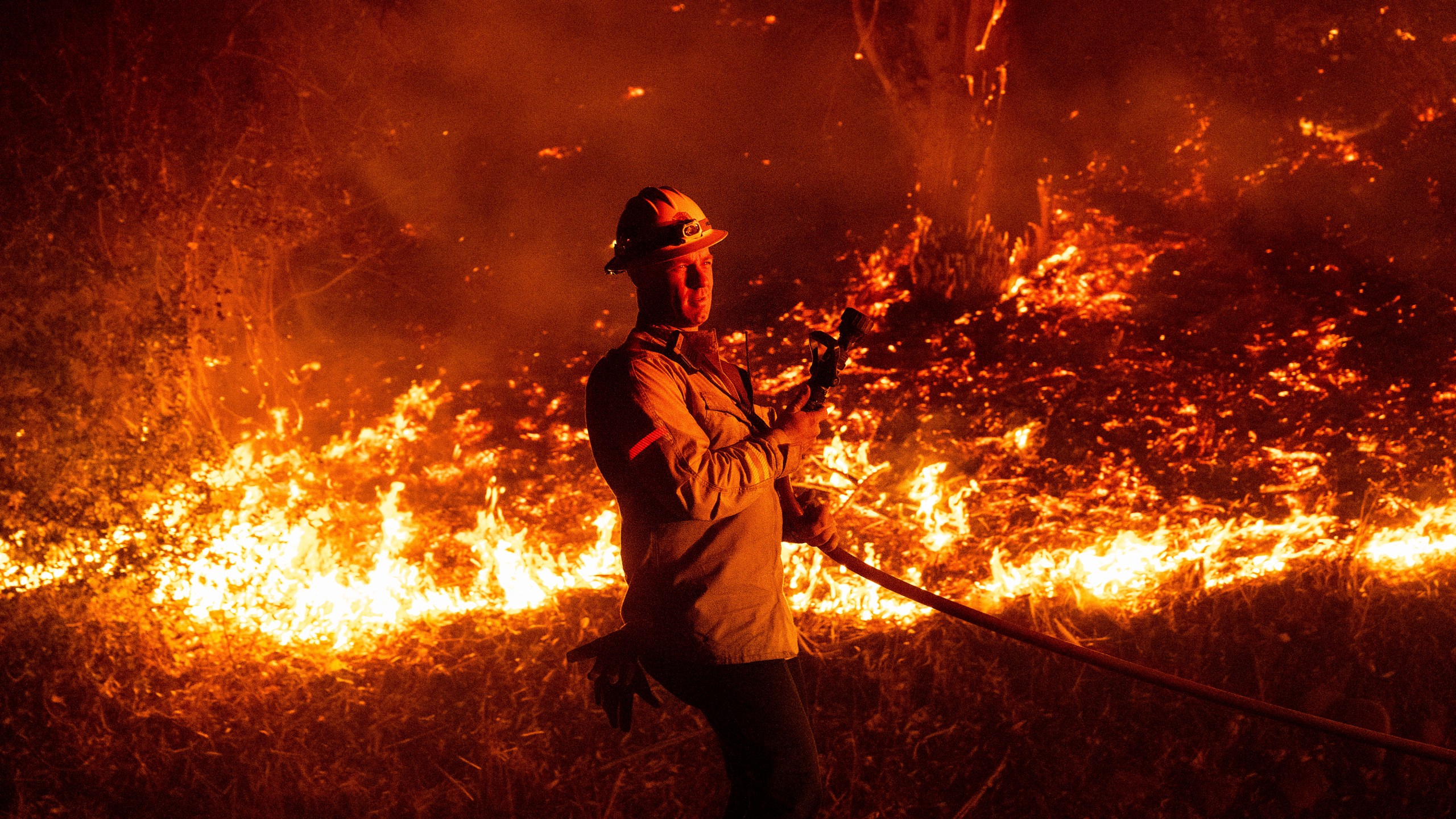 A firefighter prepares to douse flames while battling the Mountain Fire on Wednesday, Nov. 6, 2024, in Santa Paula, Calif. (AP Photo/Noah Berger)