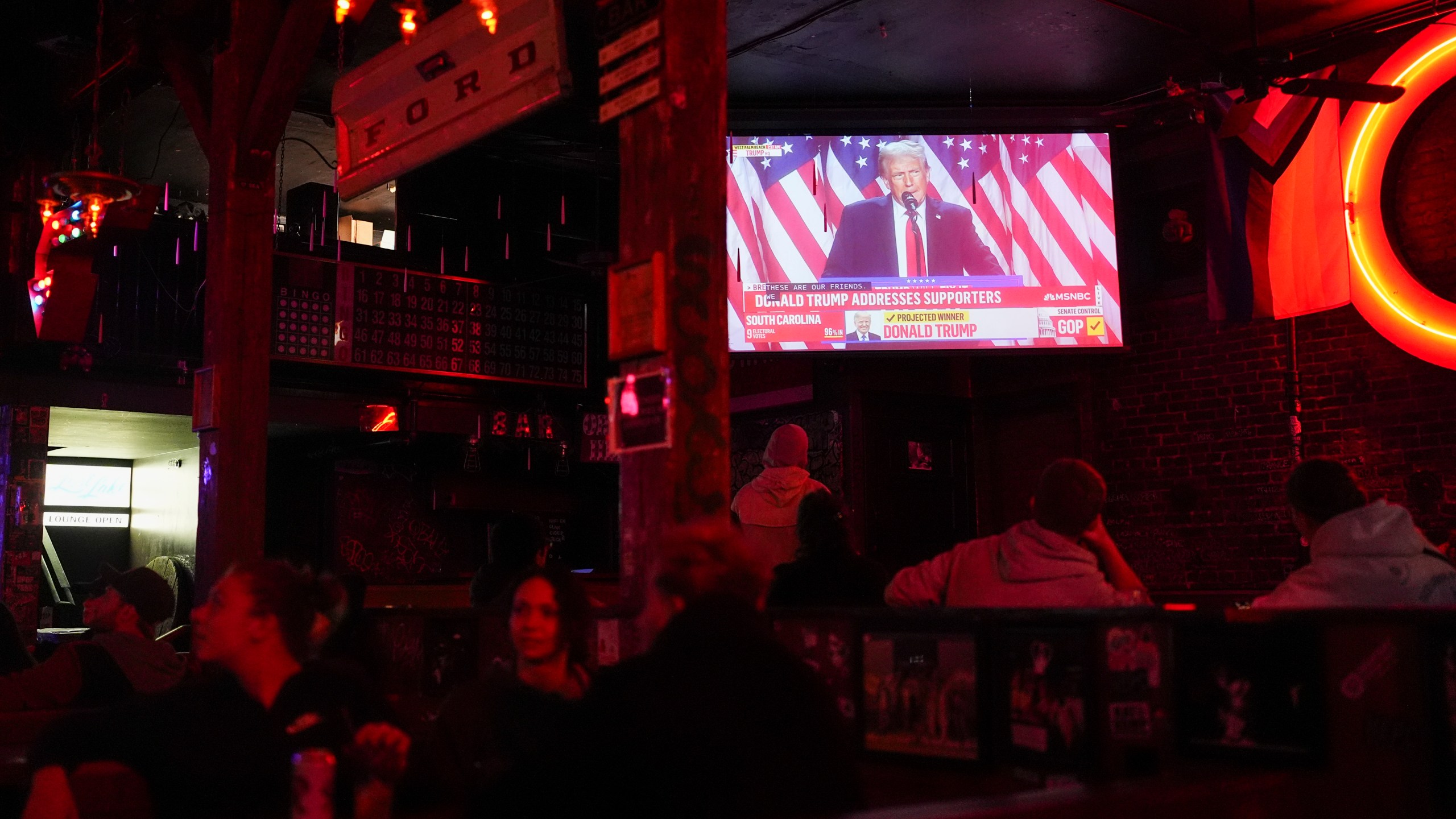 People watch as television screens show Republican presidential nominee former President Donald Trump addressing supporters on Election Day, Tuesday, Nov. 5, 2024, at Comet Tavern in Seattle. (AP Photo/Lindsey Wasson)