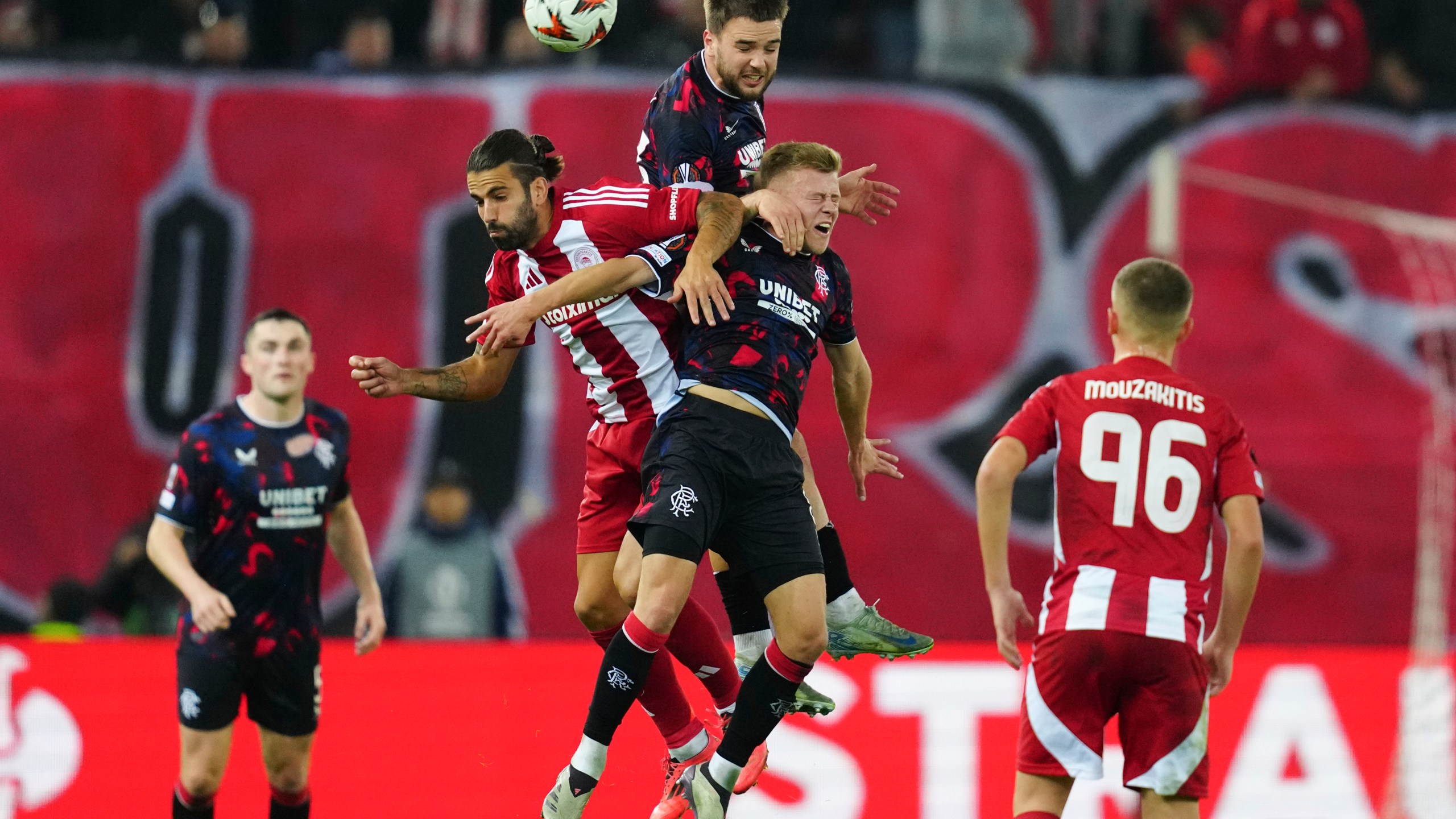 Olympiacos' Sergio Oliveira, left, jumps for the Baal among Rangers' Robin Proepper, centre and Connor Barron, right, during the Europa League opening phase soccer match between Olympiacos and Rangers at the Georgios Karaiskakis stadium at Athens' port of Piraeus, Greece, Thursday, Nov. 7, 2024. (AP Photo/Thanassis Stavrakis)