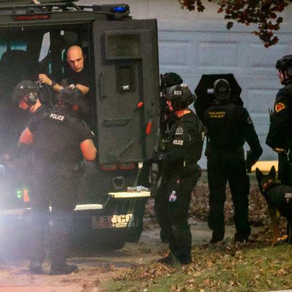 Raleigh police officers, some in tactical gear, work the scene where two people were detained Thursday afternoon, Nov. 7, 2024, on Kentford Court in Raleigh Thursday, Nov. 7, 2024, after someone repeatedly fired at cars on a busy highway near North Carolina’s capital this week, injuring one person. (Travis Long/The News & Observer via AP)