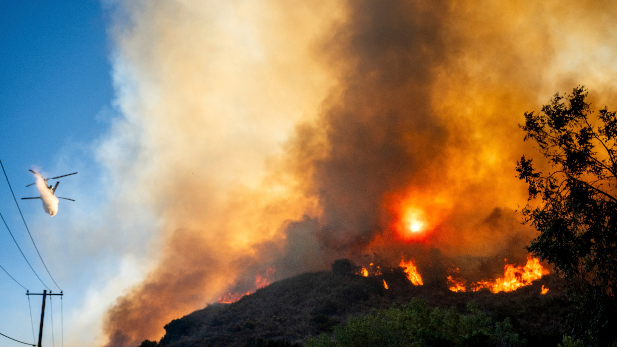 A helicopter drops water as the Mountain Fire burns along South Mountain Rd. on Thursday, Nov. 7, 2024, in Santa Paula, Calif. (AP Photo/Noah Berger)