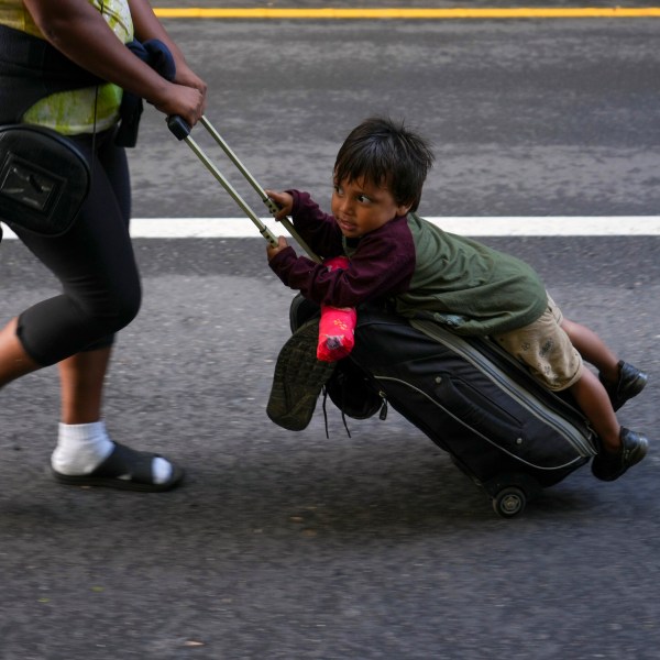 Nayely Nunez, from Honduras, uses her luggage to carry a child as she walks along the highway with a migrant caravan in Huixtla, southern Mexico, heading toward the country's northern border and ultimately the United States, Thursday, Nov. 7, 2024. (AP Photo/Moises Castillo)