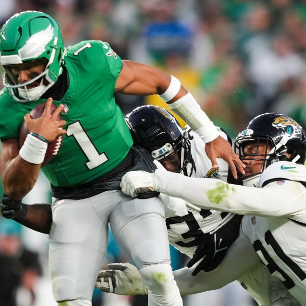 Philadelphia Eagles quarterback Jalen Hurts (1) scrambles under pressure from Jacksonville Jaguars linebacker Devin Lloyd, center, and Jaguars defensive end Arik Armstead during the first half of an NFL football game Sunday, Nov. 3, 2024, in Philadelphia. (AP Photo/Matt Slocum)