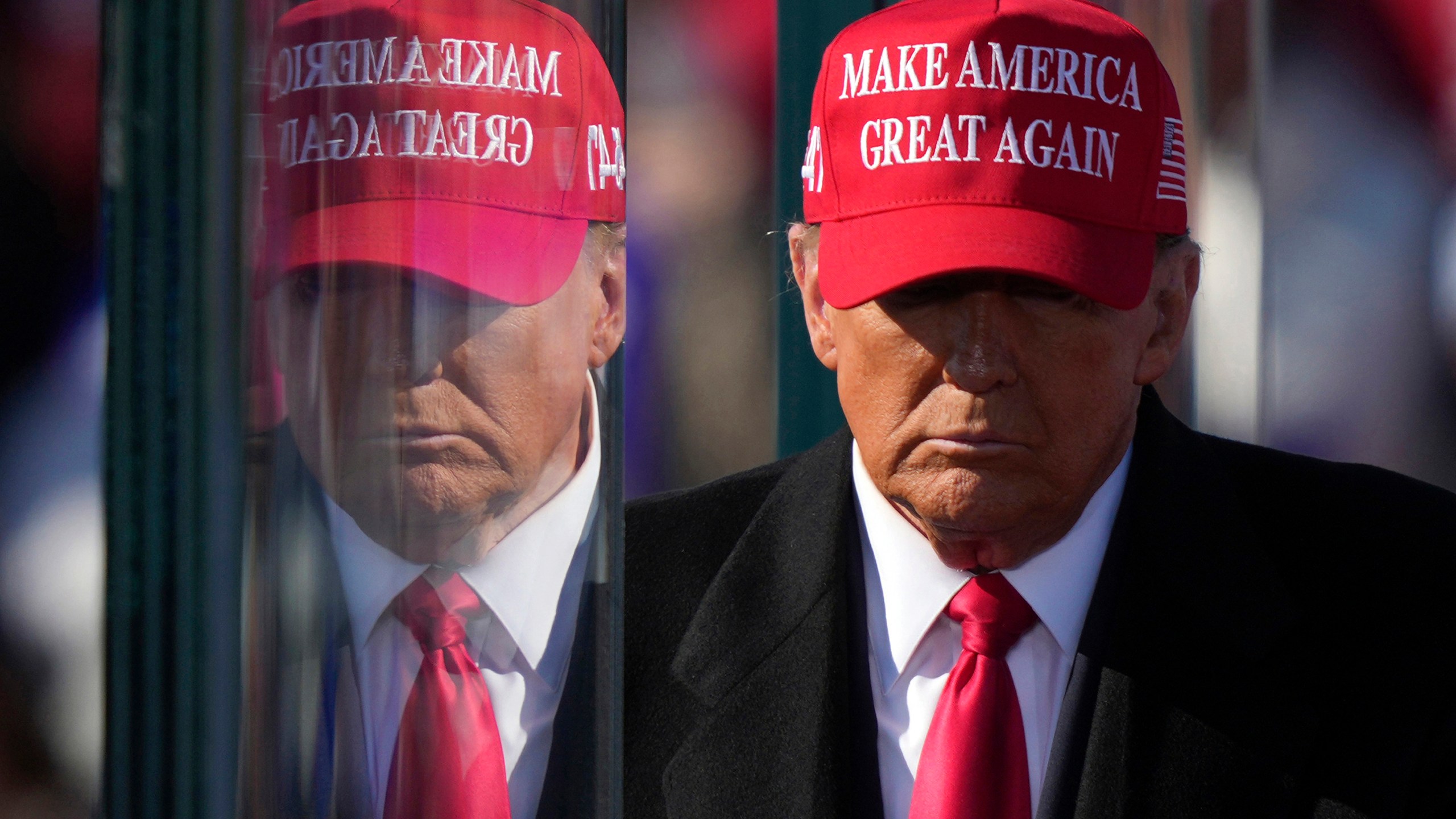 FILE - Republican presidential nominee former President Donald Trump is reflected in the bullet proof glass as he finishes speaking at a campaign rally in Lititz, Pa., Nov. 3, 2024. (AP Photo/Matt Rourke, File)