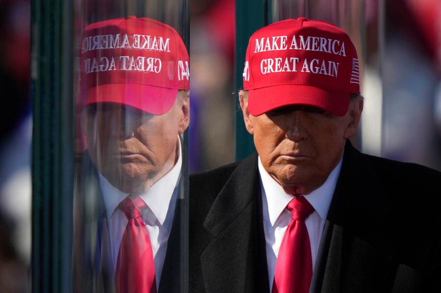 FILE - Republican presidential nominee former President Donald Trump is reflected in the bullet proof glass as he finishes speaking at a campaign rally in Lititz, Pa., Nov. 3, 2024. (AP Photo/Matt Rourke, File)