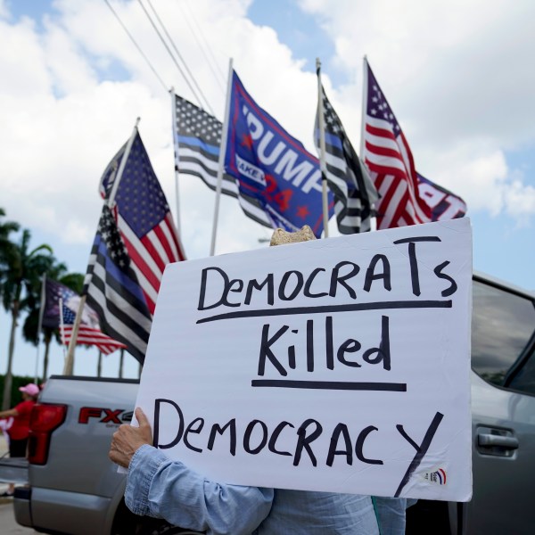 FILE - A supporter of former President Donald Trump holds a sign outside Trump International Golf Club, April 2, 2023, in West Palm Beach, Fla. (AP Photo/Evan Vucci, File)