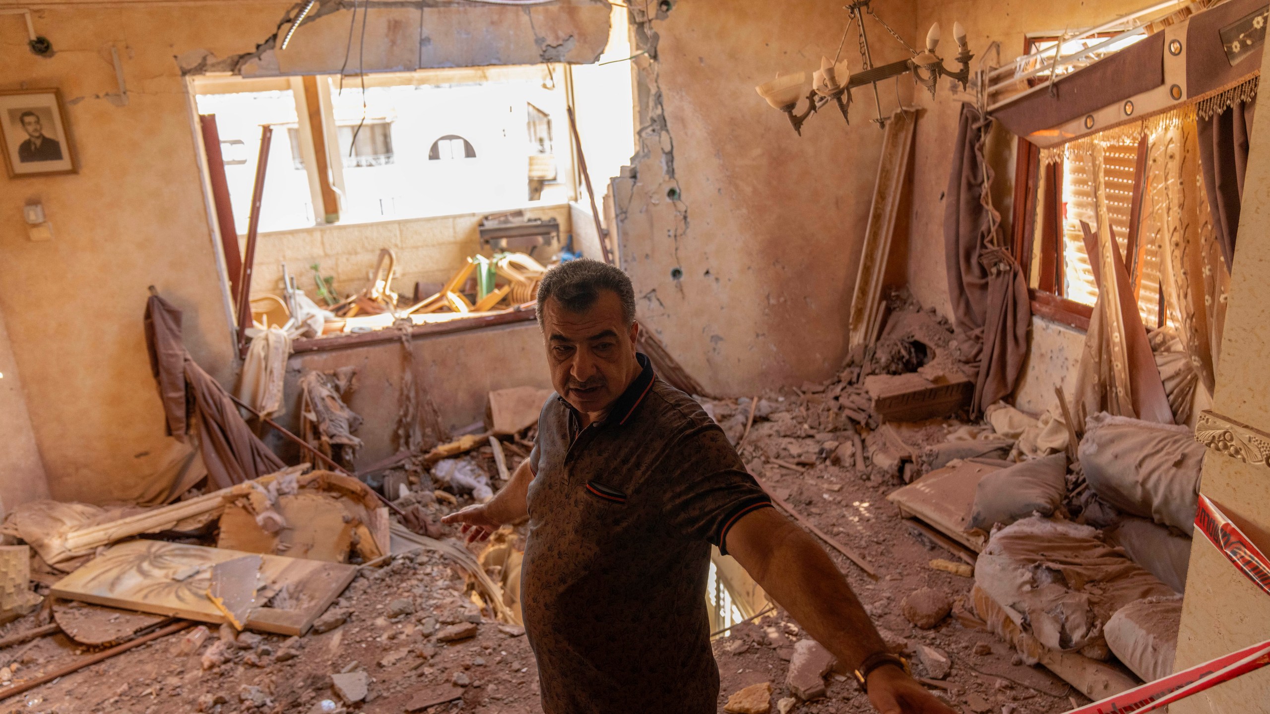 A local resident stands next to debris inside his house after it was struck by projectiles fired from Lebanon in Kfar Yasif, north west Israel, Saturday, Nov. 9, 2024. (AP Photo/Francisco Seco)