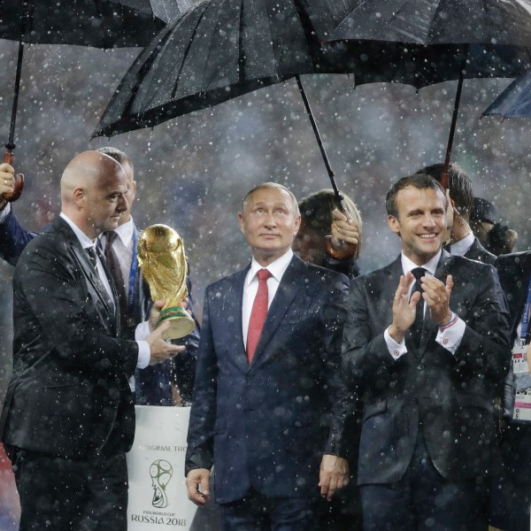 FILE - From left to right, FIFA President Gianni Infantino, Russia's President Vladimir Putin, France's President Emmanuel Macron and Croatia's President Kolinda Grabar-Kitarovic stand under the pouring rain during the awards ceremony after final match between France and Croatia at the 2018 soccer World Cup in the Luzhniki Stadium in Moscow, Russia, Sunday, July 15, 2018. (AP Photo/Natacha Pisarenko, File)