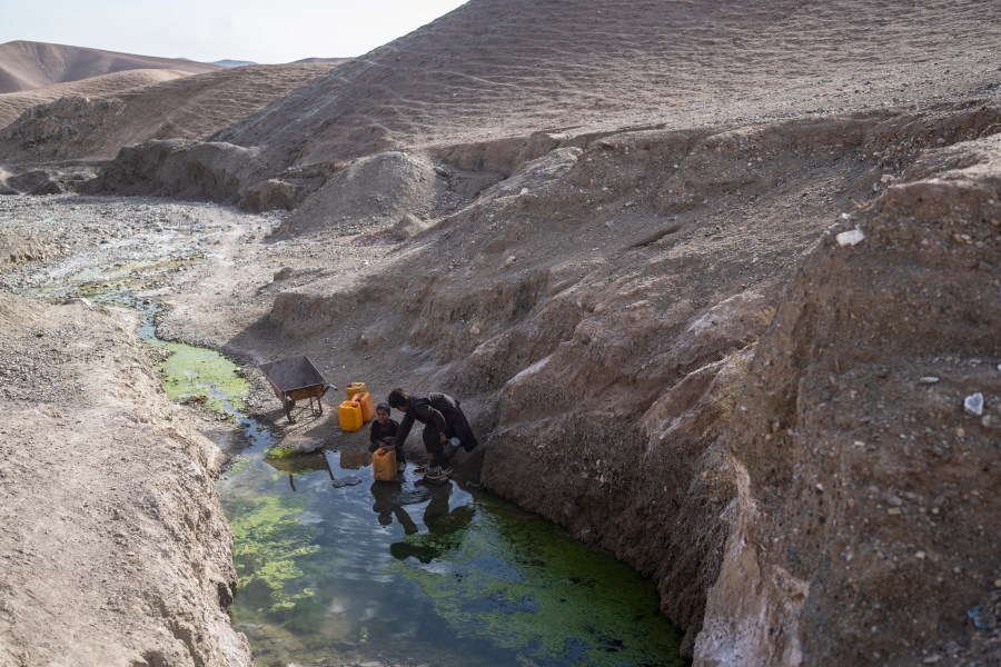 FILE -Two brothers fill canisters with water from a stagnant pool about 3 kilometers (2 miles) from their home in Kamar Kalagh village outside Herat, Afghanistan, Friday, Nov. 26, 2021. (AP Photo/Petros Giannakouris, File)