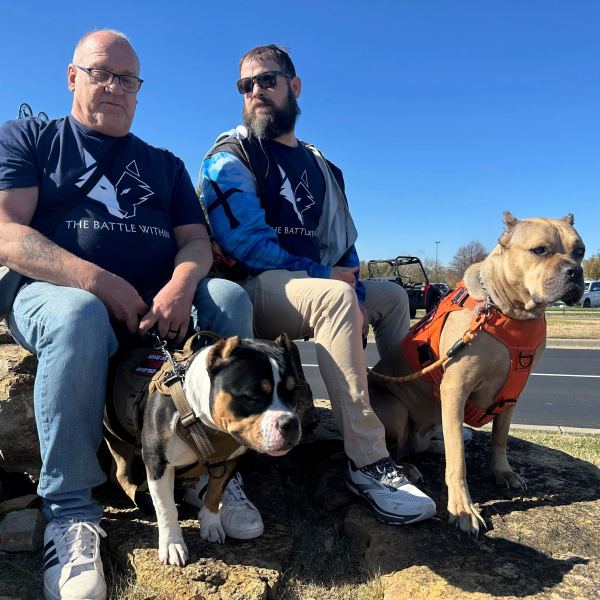 Retired Army First Sgt. Timothy Siebenmorgen, left, and retired Marine Corps Cpl. Mark Atkinson sit with their service dogs, Rosie and Lexi on Thursday, Nov. 7, 2024, in Kansas City, Kan., during a group training session. Both veterans are part of Dogs 4 Valor that helps retired veterans and first responders in the Kansas City area work with their service dogs to help manage depression, anxiety and other challenges. (AP Photo/Nick Ingram)