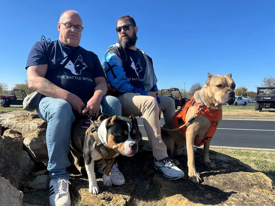 Retired Army First Sgt. Timothy Siebenmorgen, left, and retired Marine Corps Cpl. Mark Atkinson sit with their service dogs, Rosie and Lexi on Thursday, Nov. 7, 2024, in Kansas City, Kan., during a group training session. Both veterans are part of Dogs 4 Valor that helps retired veterans and first responders in the Kansas City area work with their service dogs to help manage depression, anxiety and other challenges. (AP Photo/Nick Ingram)