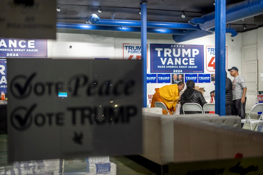 A sign hangs in the window as volunteers meet in the campaign office for Republican presidential nominee former President Donald Trump, Monday, Nov. 4, 2024, in Hamtramck, Mich. (AP Photo/David Goldman)