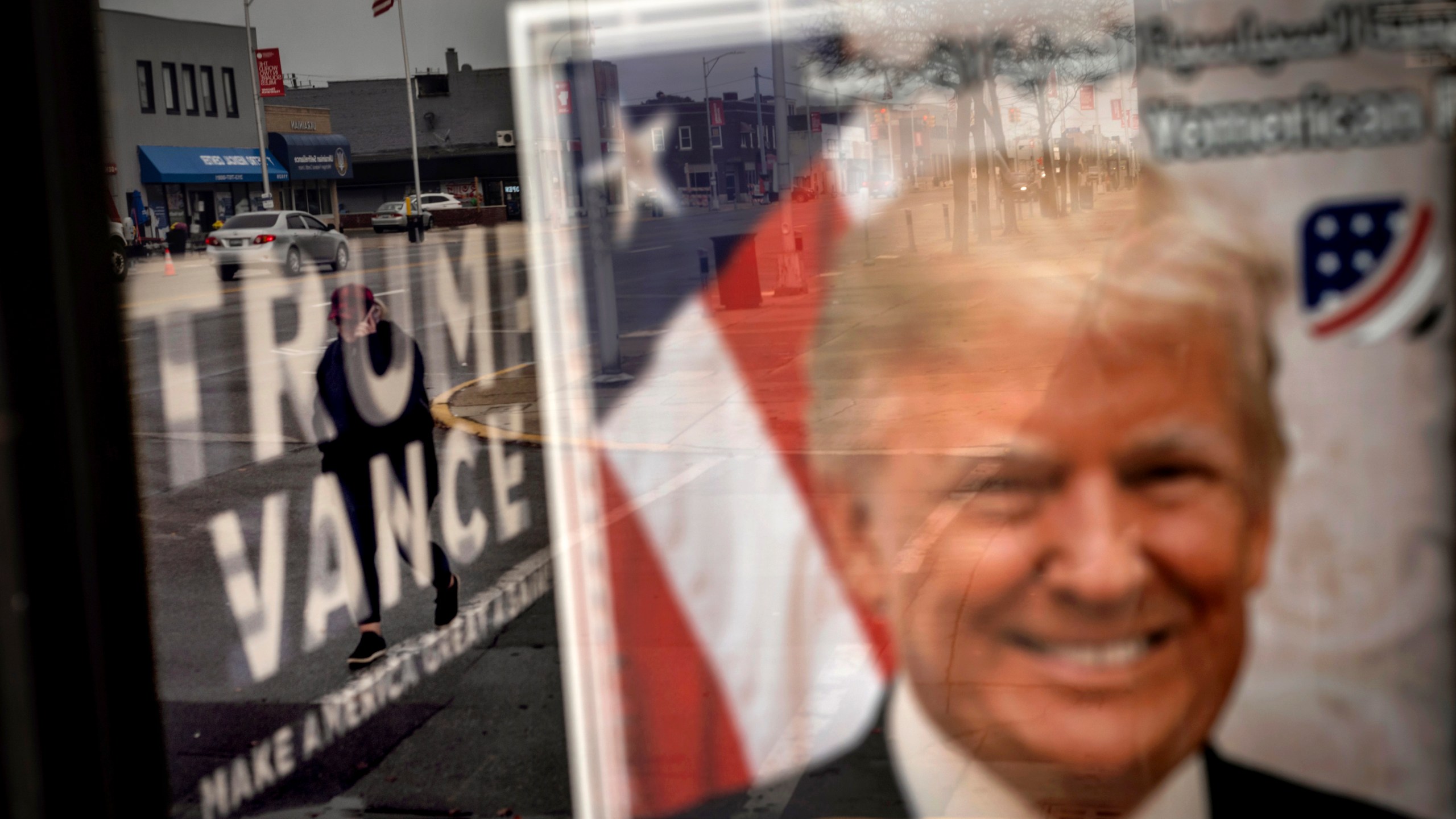 An image of Republican presidential nominee former President Donald Trump hangs in the window of a campaign office as a pedestrian passes by Monday, Nov. 4, 2024, in Hamtramck, Mich. (AP Photo/David Goldman)