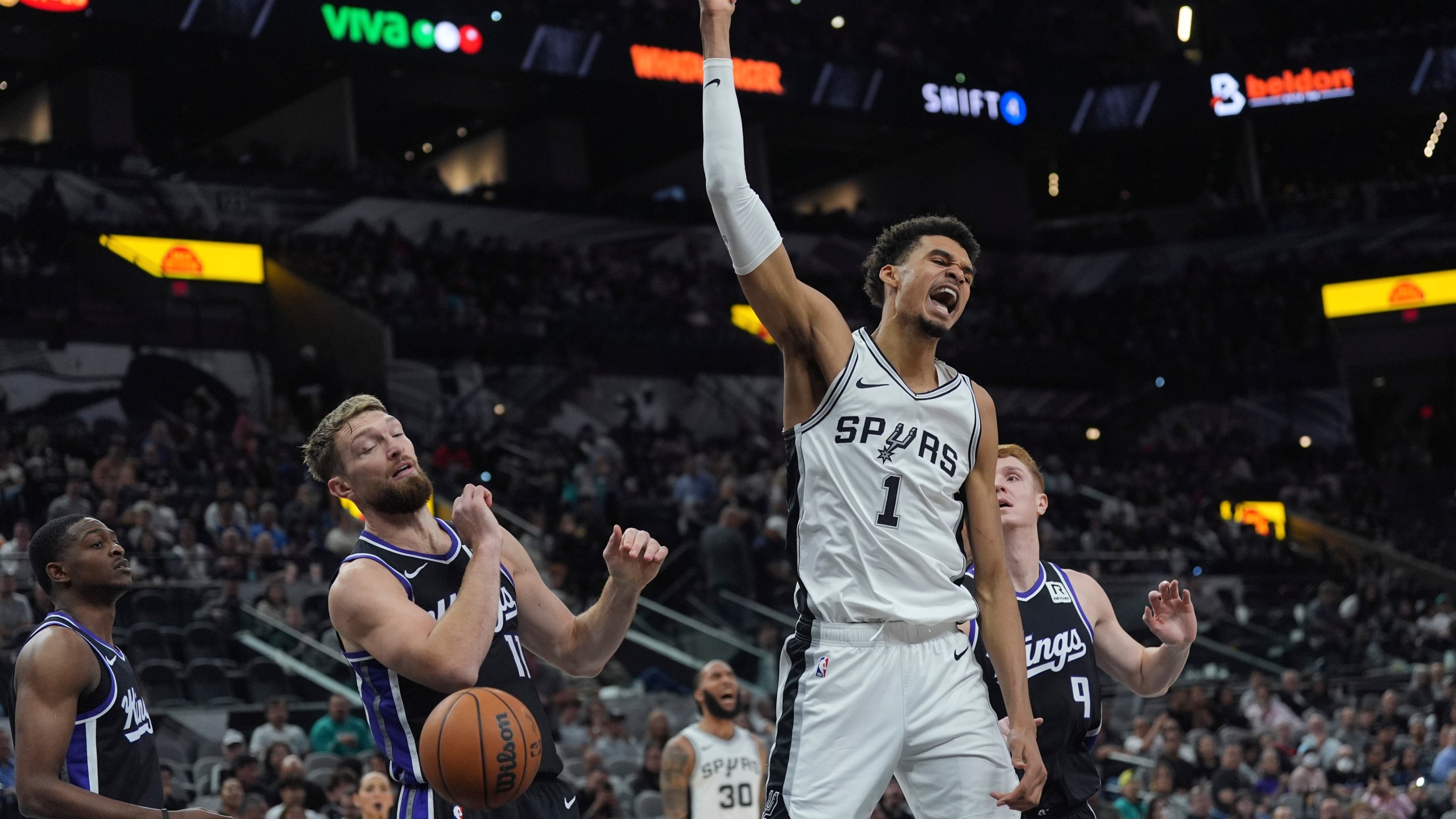 San Antonio Spurs center Victor Wembanyama (1) reacts as he scores over Sacramento Kings forward Domantas Sabonis (11) during the second half of an NBA basketball game in San Antonio, Monday, Nov. 11, 2024. (AP Photo/Eric Gay)