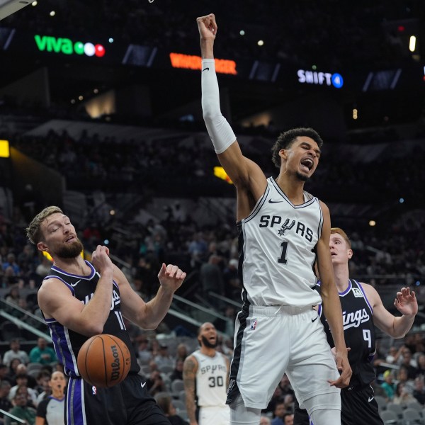 San Antonio Spurs center Victor Wembanyama (1) reacts as he scores over Sacramento Kings forward Domantas Sabonis (11) during the second half of an NBA basketball game in San Antonio, Monday, Nov. 11, 2024. (AP Photo/Eric Gay)