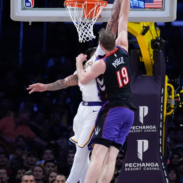 Los Angeles Lakers forward Anthony Davis, left, blocks a shot from Toronto Raptors center Jakob Poeltl (19) during the second half of an NBA basketball game Sunday, Nov. 10, 2024, in Los Angeles. (AP Photo/Marcio Jose Sanchez)