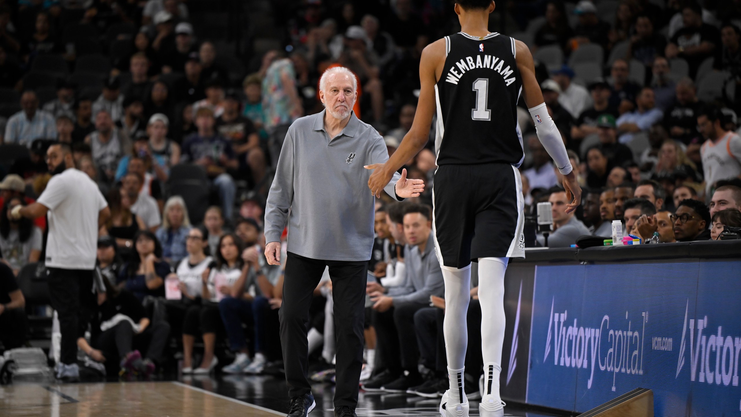 San Antonio Spurs head coach Gregg Popovich, left, greets Spurs forward Victor Wembanyama as he walks off of the court during the first half of an NBA basketball game against the Houston Rockets, Monday, Oct. 28, 2024, in San Antonio. (AP Photo/Darren Abate)