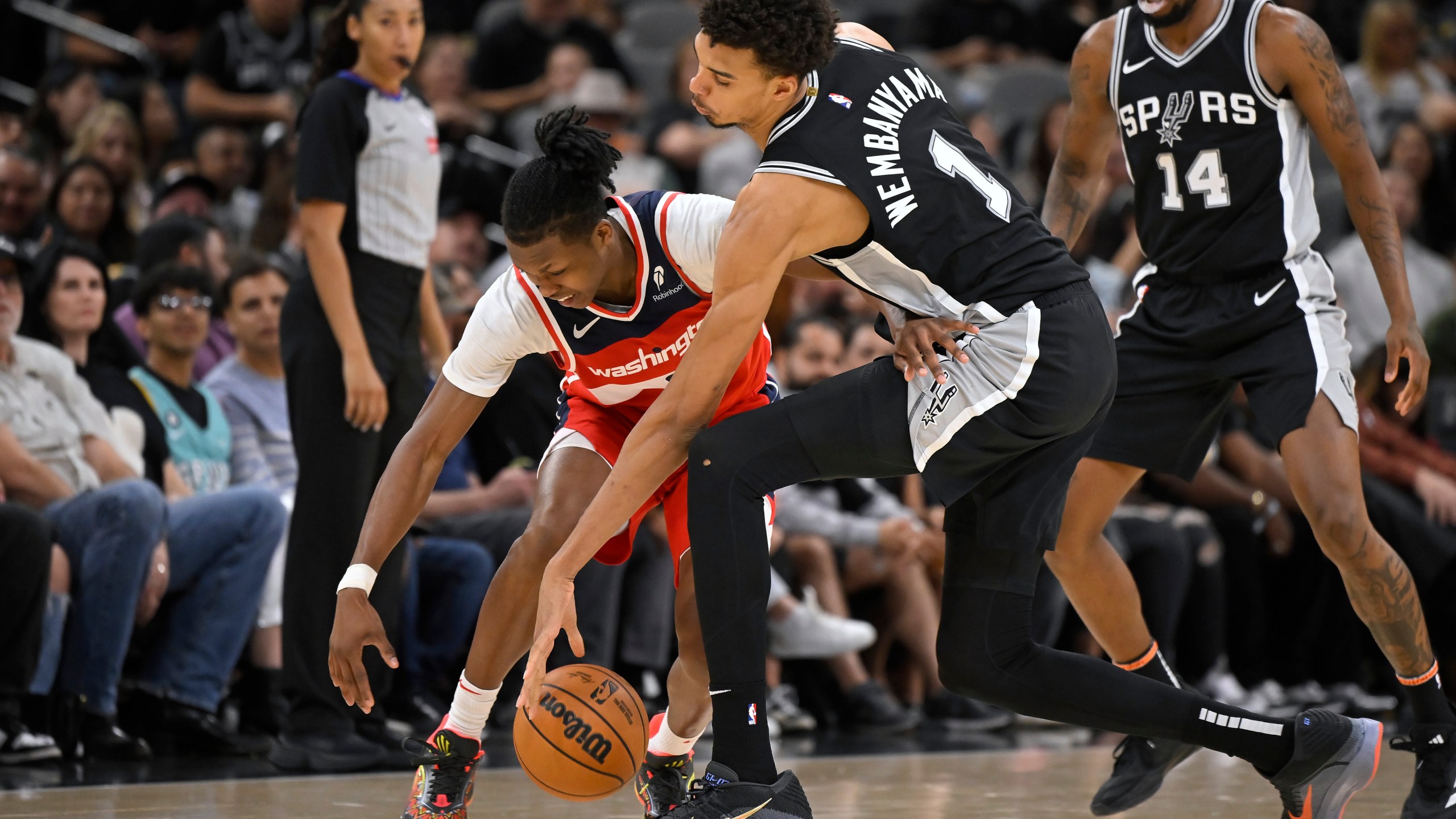 San Antonio Spurs forward Victor Wembanyama (1) and Washington Wizards guard Bub Carrington fight for possession during the second half of an NBA basketball game, Wednesday, Nov. 13, 2024, in San Antonio. San Antonio won 139-130. (AP Photo/Darren Abate)