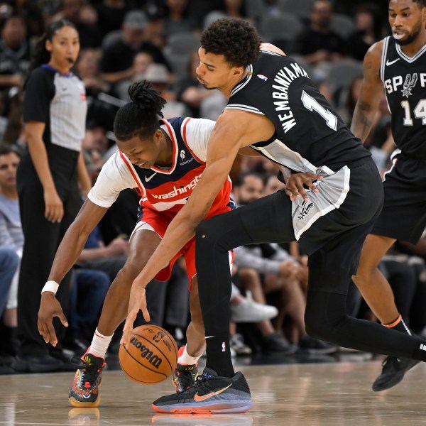 San Antonio Spurs forward Victor Wembanyama (1) and Washington Wizards guard Bub Carrington fight for possession during the second half of an NBA basketball game, Wednesday, Nov. 13, 2024, in San Antonio. San Antonio won 139-130. (AP Photo/Darren Abate)