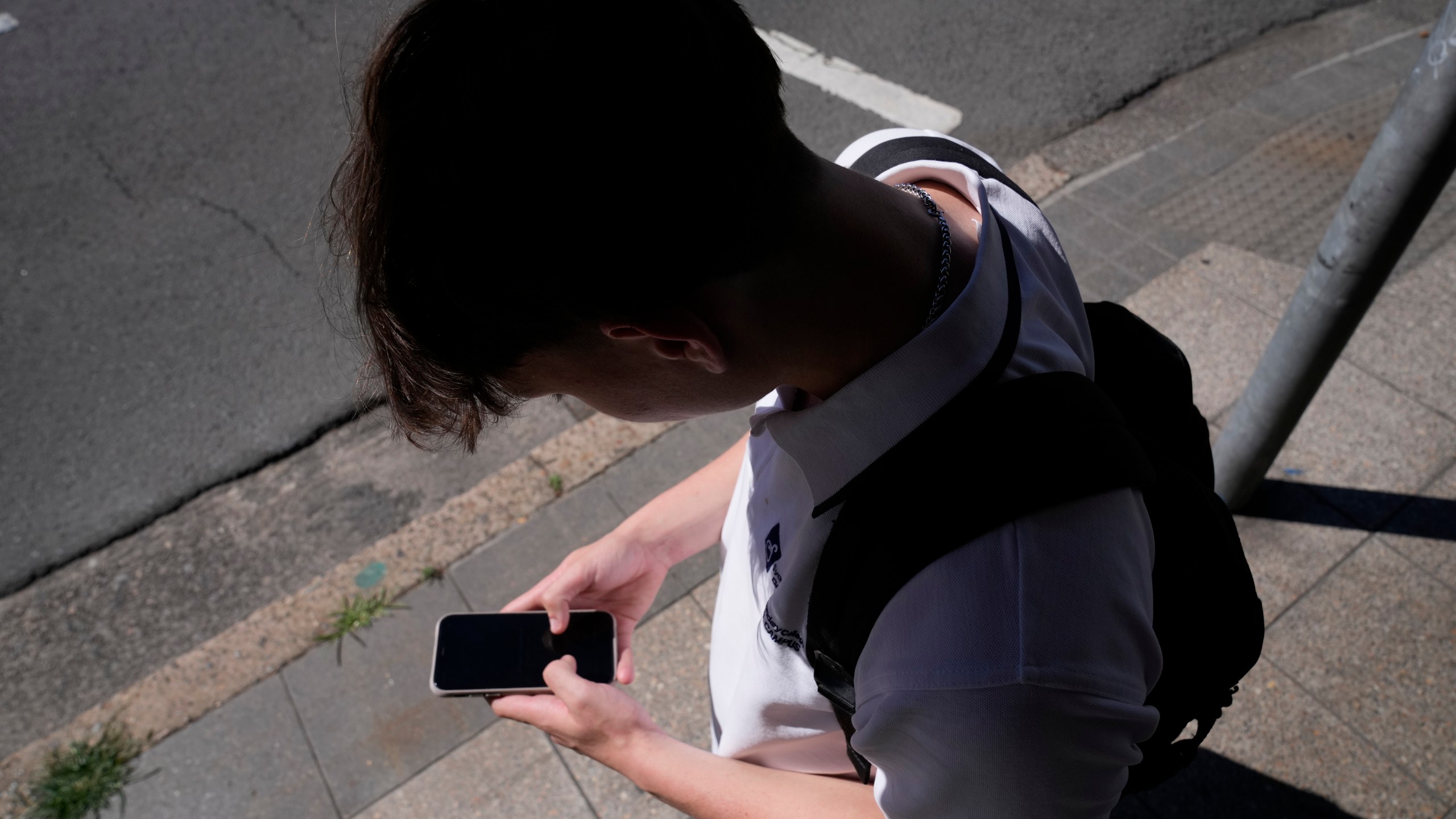 A teenage boy uses his phone in Sydney, Friday, Nov. 8, 2024. (AP Photo/Rick Rycroft)