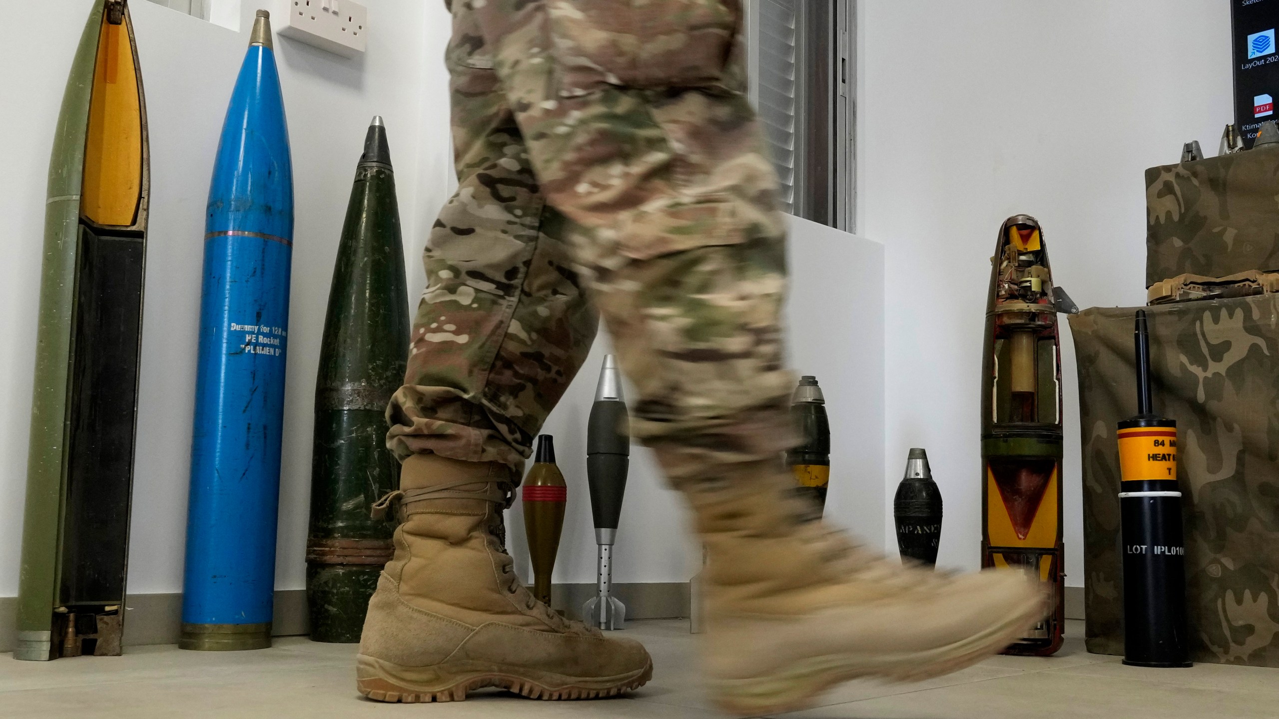 A Cypriot National Guardsman walks in front of a display of inert rockets, artillery shells and other munitions as part of a training course of Ukrainian personnel in the disposal of landmines and other explosive ordnance in Cyprus, at an army base in Nicosia, Thursday, Nov. 14, 2024. (AP Photo/Petros Karadjias)