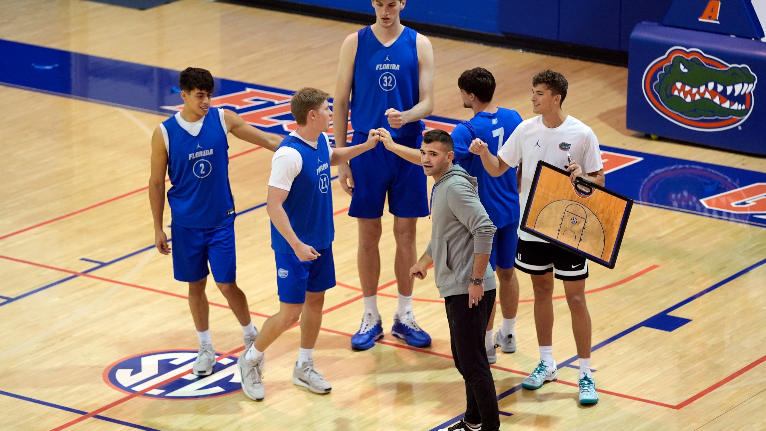 Olivier Rioux, back center, a 7-foot-9 NCAA college basketball player at Florida, gathers with coaches and teammates at the team's practice, Friday, Oct. 18, 2024, in Gainesville, Fla. (AP Photo/John Raoux)