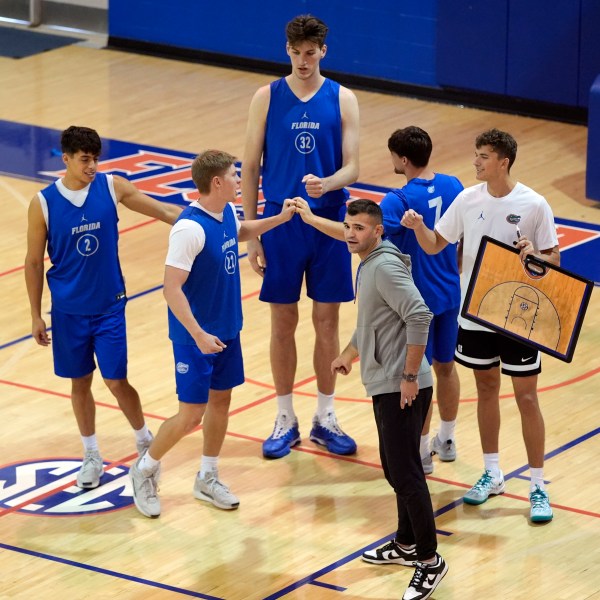 Olivier Rioux, back center, a 7-foot-9 NCAA college basketball player at Florida, gathers with coaches and teammates at the team's practice, Friday, Oct. 18, 2024, in Gainesville, Fla. (AP Photo/John Raoux)