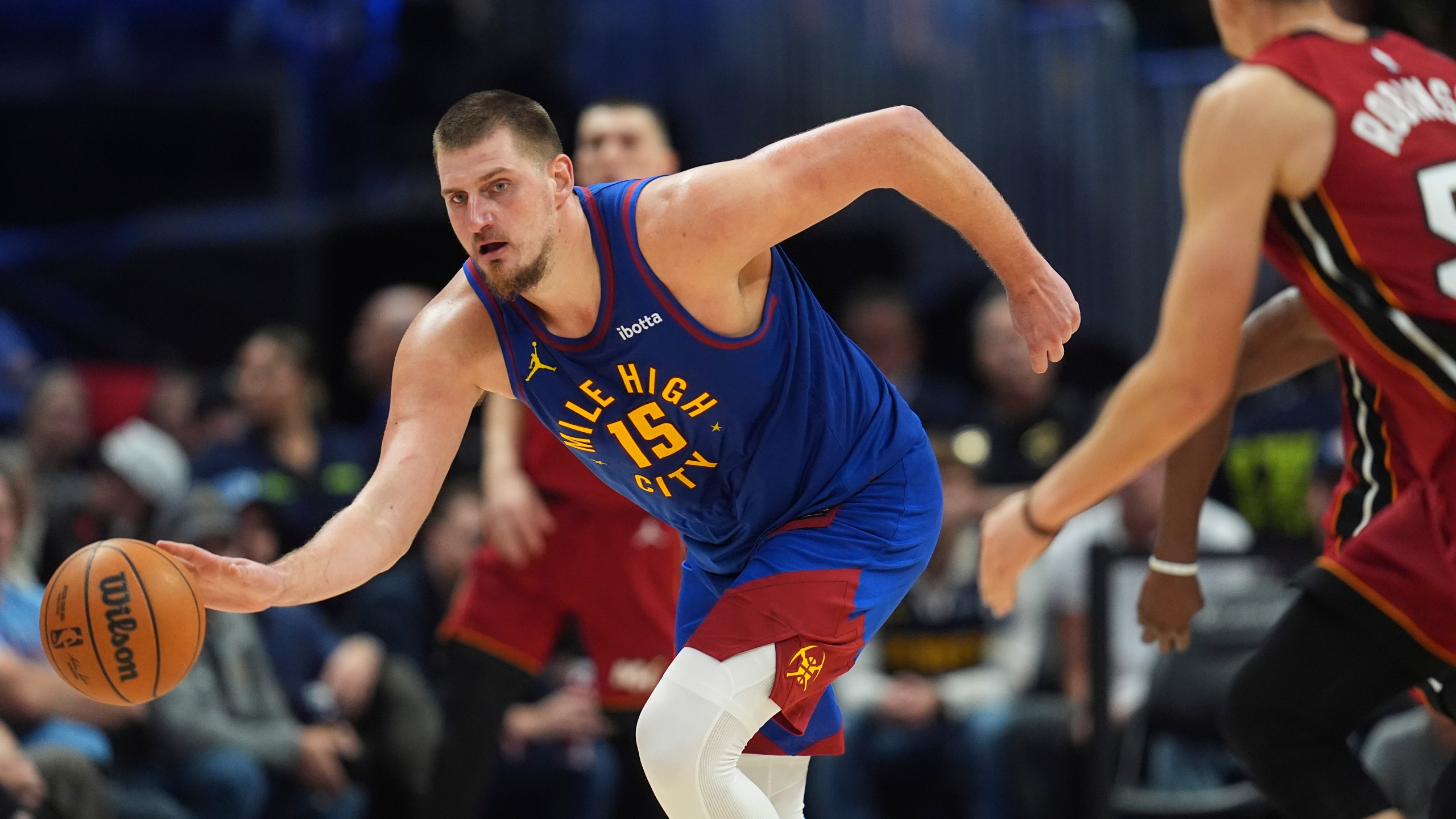 Denver Nuggets center Nikola Jokic, left, collects a loose ball as Miami Heat forward Duncan Robinson defends in the second half of an NBA basketball game Friday, Nov. 8, 2024, in Denver. (AP Photo/David Zalubowski)