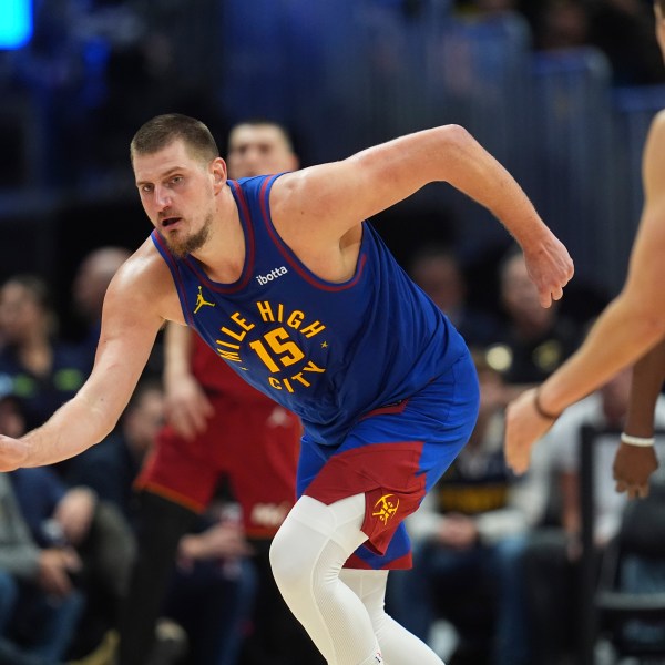 Denver Nuggets center Nikola Jokic, left, collects a loose ball as Miami Heat forward Duncan Robinson defends in the second half of an NBA basketball game Friday, Nov. 8, 2024, in Denver. (AP Photo/David Zalubowski)