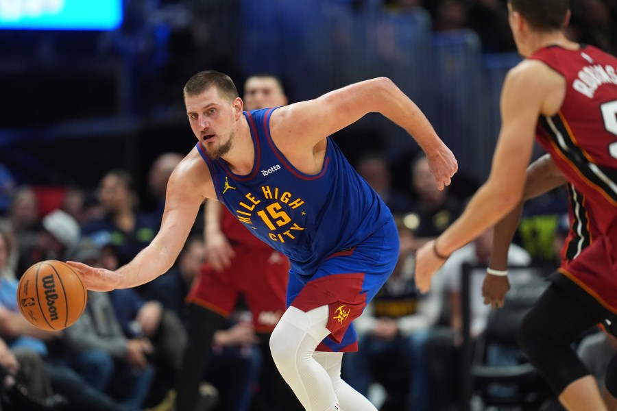 Denver Nuggets center Nikola Jokic, left, collects a loose ball as Miami Heat forward Duncan Robinson defends in the second half of an NBA basketball game Friday, Nov. 8, 2024, in Denver. (AP Photo/David Zalubowski)