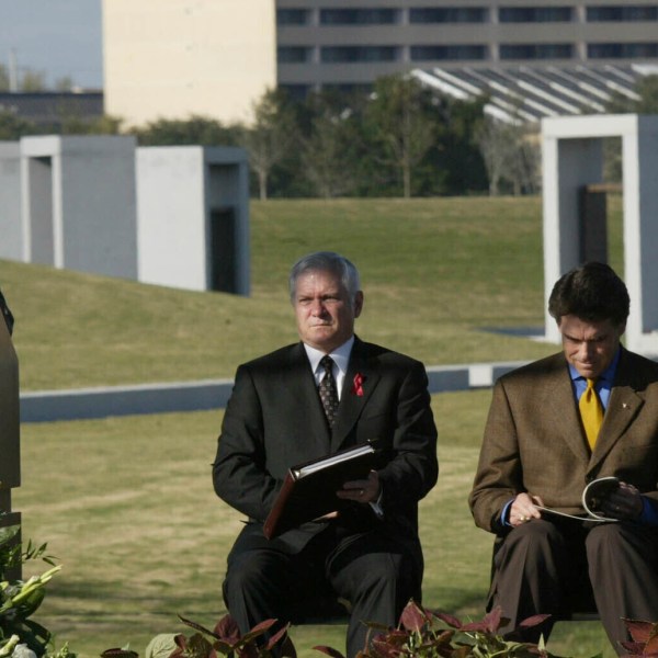 FILE - Jerry Ebanks, left, whose son Michael Ebanks was killed in the 1999 bonfire collapse, speaks at the Bonfire Memorial dedication at Texas A&M University in College Station, Nov. 18, 2004. In back from left to right is University President Dr. Robert M. Gates; Texas Gov. Rick Perry; and Student Body President Jackson Hildebrand. (AP Photo/Donna McWilliam, File)