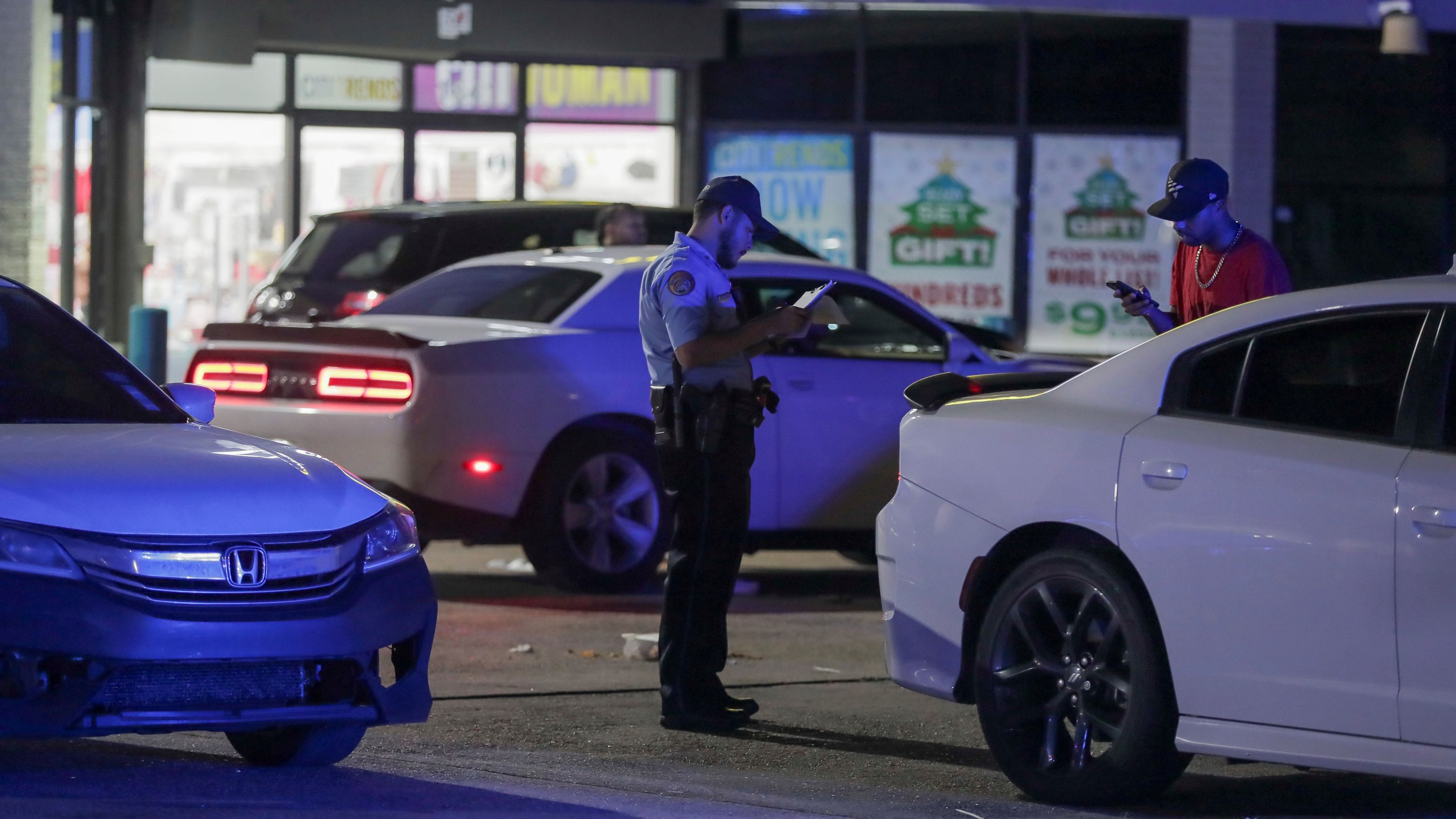 A New Orleans police officer takes a report at the scene in the Save O Lot parking lot where several people were shot and killed in New Orleans Sunday Nov. 17, 2024. (David Grunfeld/The Times-Picayune/The New Orleans Advocate via AP)