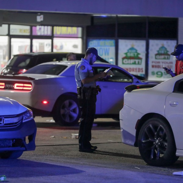 A New Orleans police officer takes a report at the scene in the Save O Lot parking lot where several people were shot and killed in New Orleans Sunday Nov. 17, 2024. (David Grunfeld/The Times-Picayune/The New Orleans Advocate via AP)