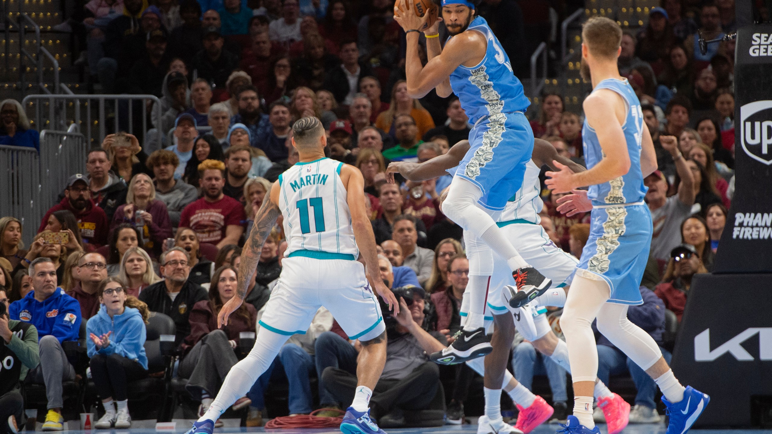 Cleveland Cavaliers' Jarrett Allen, center, grabs a rebound as Charlotte Hornets' Cody Martin (11) and Dean Wade, right, look on during the second half of an NBA basketball game in Cleveland, Sunday, Nov 17, 2024. (AP Photo/Phil Long)